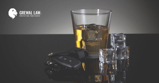 A glass of alcohol and a set of car keys next to it.